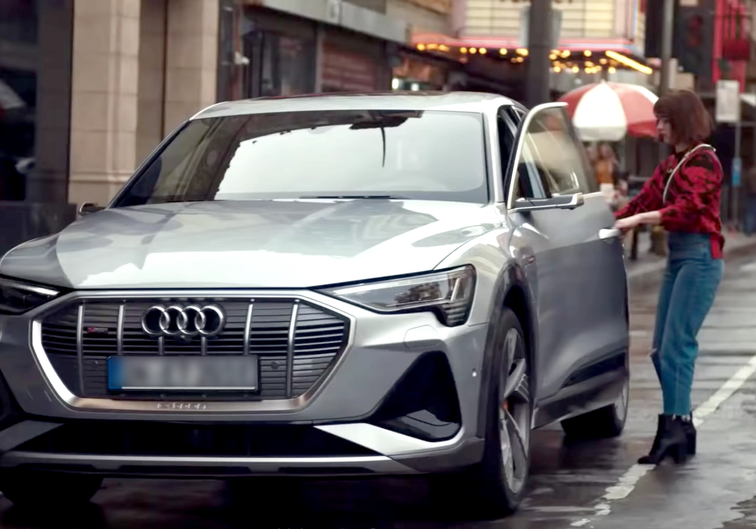 A woman is standing next to a silver Audi SUV, oblivious to one of the biggest marketing fails in recent memory.