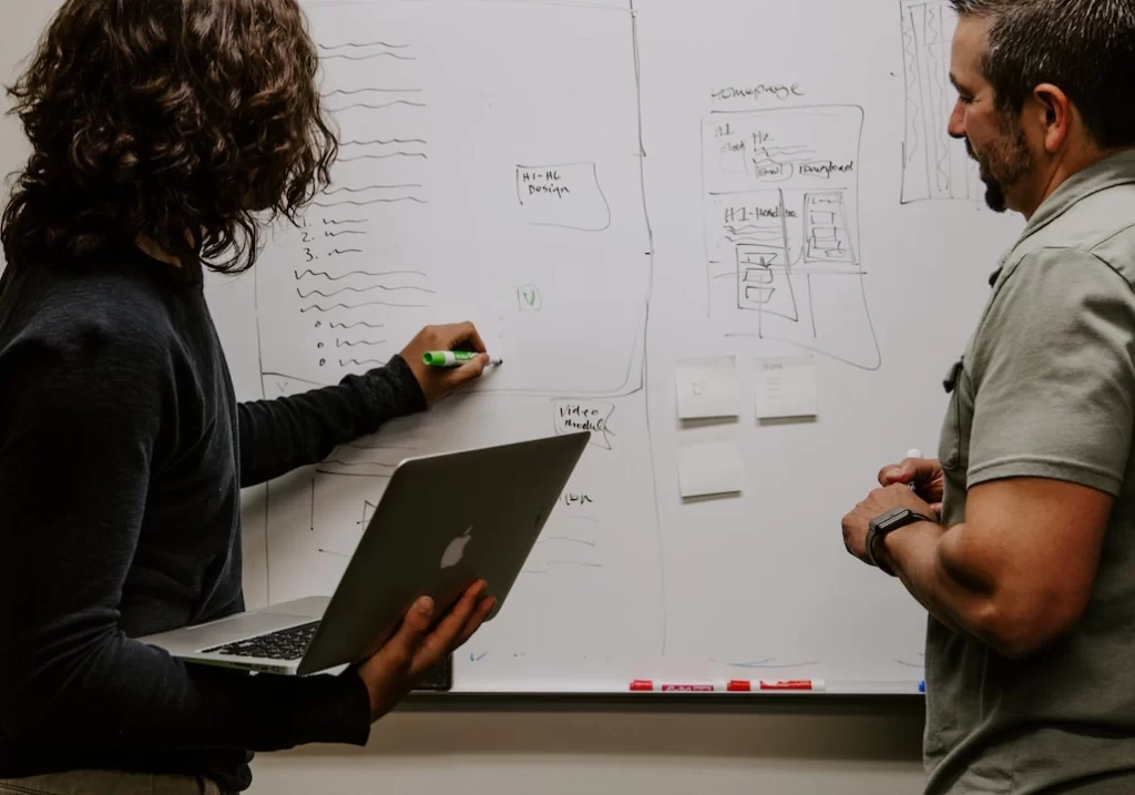 Two people collaborating on a whiteboard for their million-dollar business.