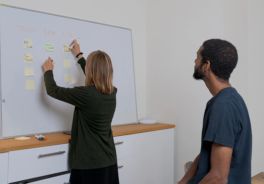 A woman strategizing for her million-dollar business, writing on a whiteboard.