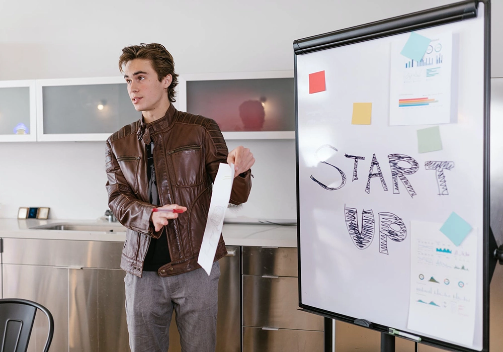 A man standing in front of a whiteboard with "start up" and "million-dollar business" written on it.