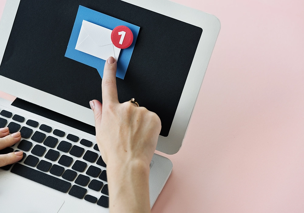 A woman's hand is leverage, pointing at an envelope on a laptop to leverage the power of social media.
