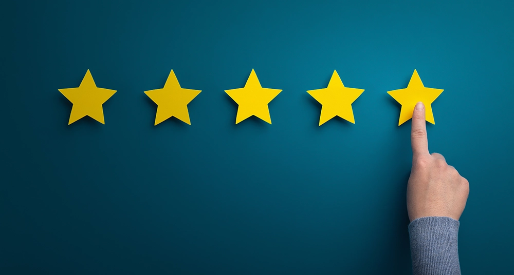 A person's finger is pointing at five stars on a blue background, embodying social proof.
