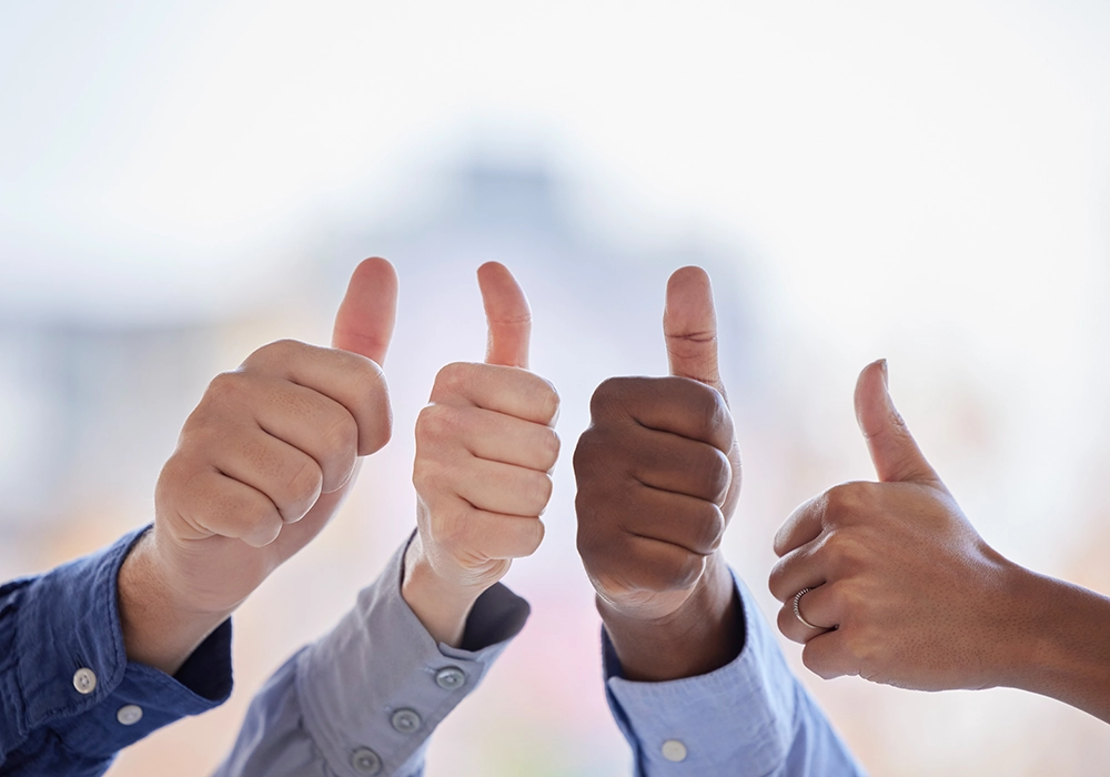 A group of people showing social proof with thumbs up.