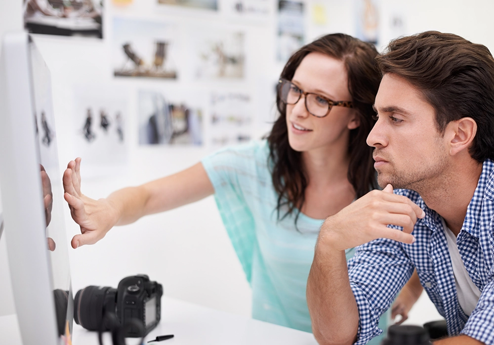 A man and woman assessing a website's credibility while looking at a computer screen.