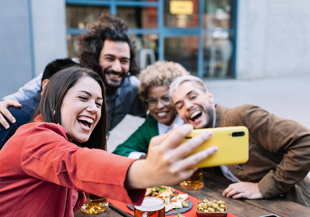 A group of friends leveraging social media by taking a selfie at a restaurant.