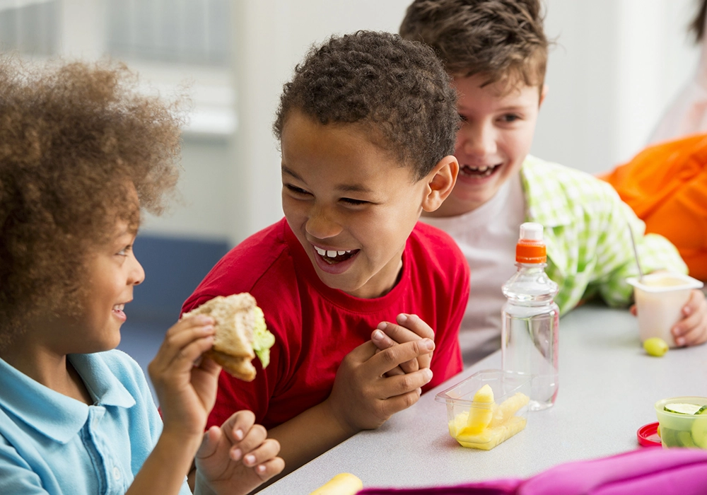 Children laughing and enjoying snacks together, embodying Social Proof Theory.