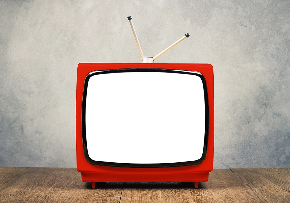 A traditional advertising medium - a red TV with a blank screen - placed on a wooden table.