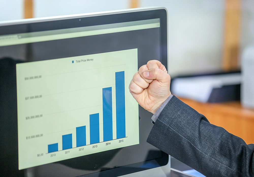 Person giving a thumbs-up in front of a computer screen displaying a bar graph with an increasing trend, illustrating the typical conversion rate.