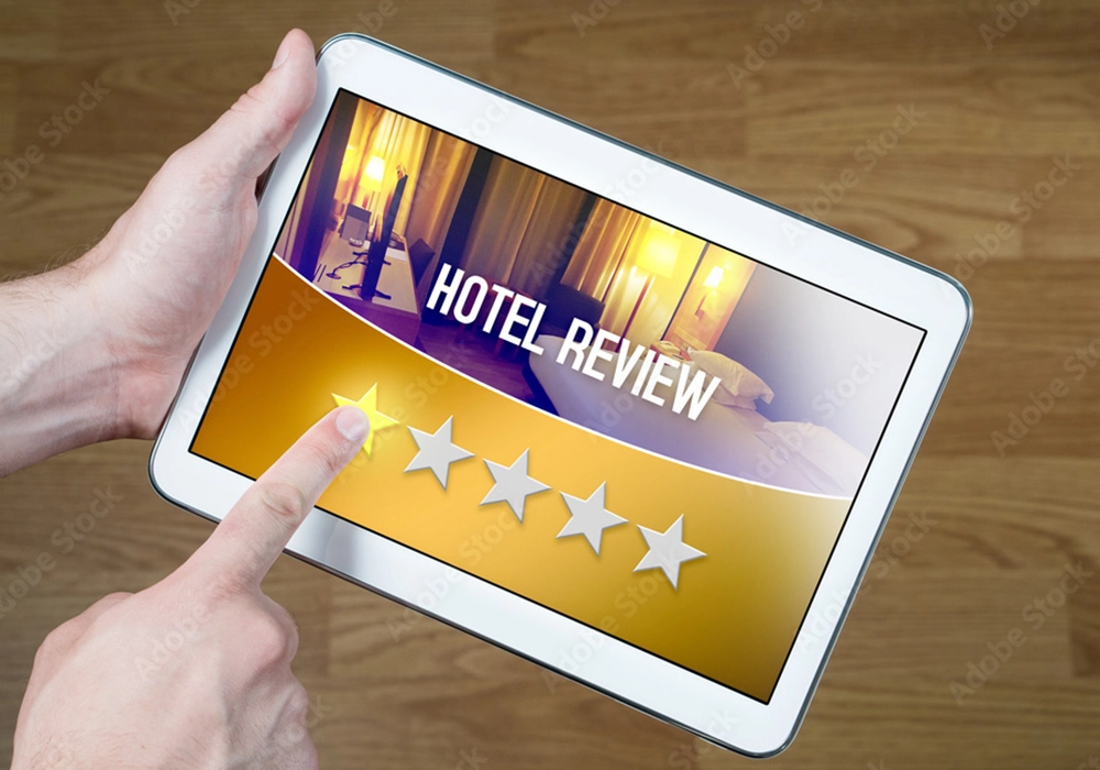 A person's hand touching a tablet screen displaying a 4-star hotel review rating, exemplifying Social Proof Theory.
