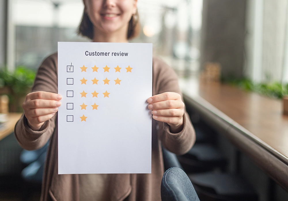 Woman holding a paper showing a five-star customer review rating for website testimonials.