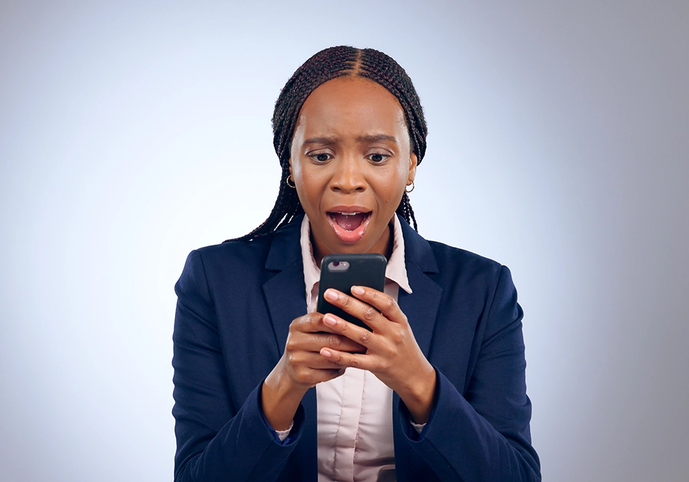 Woman in business attire expressing surprise while reading website testimonials on her smartphone.