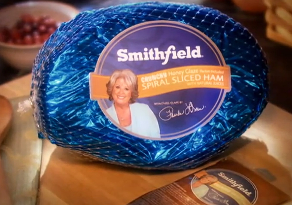 A sealed Smithfield crunchy honey glaze spiral sliced ham in blue packaging with a label featuring a celebrity's image, notorious for endorsements gone wrong.