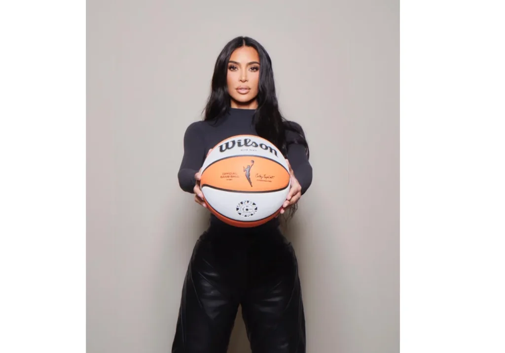 Kim in black top and leather pants holding a basketball autographed by a most successful celebrity endorsement.