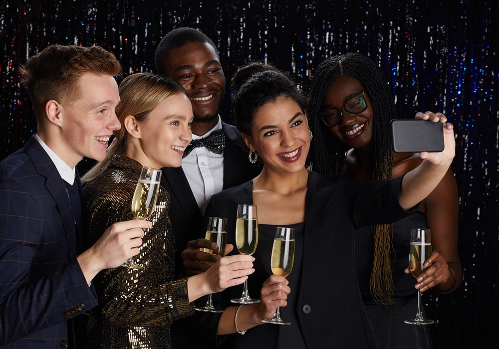 Group of friends taking a selfie while toasting with champagne at a celebration featuring a celebrity endorsement.