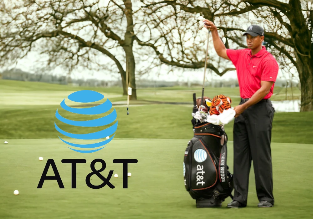 Tiger Wood in a red shirt selecting a club from his bag on a golf course, with the AT&T logo visible on the bag and displayed prominently in the foreground amidst celebrity endorsements gone wrong.