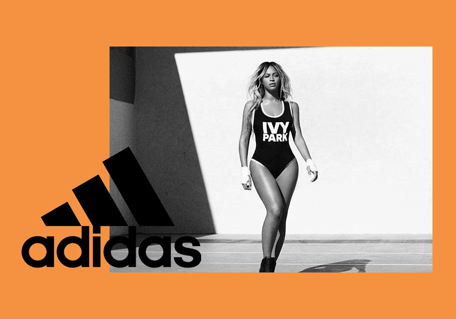 Beyoncé in an ivy park bodysuit poses confidently near a shadowed wall, with the adidas logo prominently displayed in the foreground as part of their endorsement partnership.