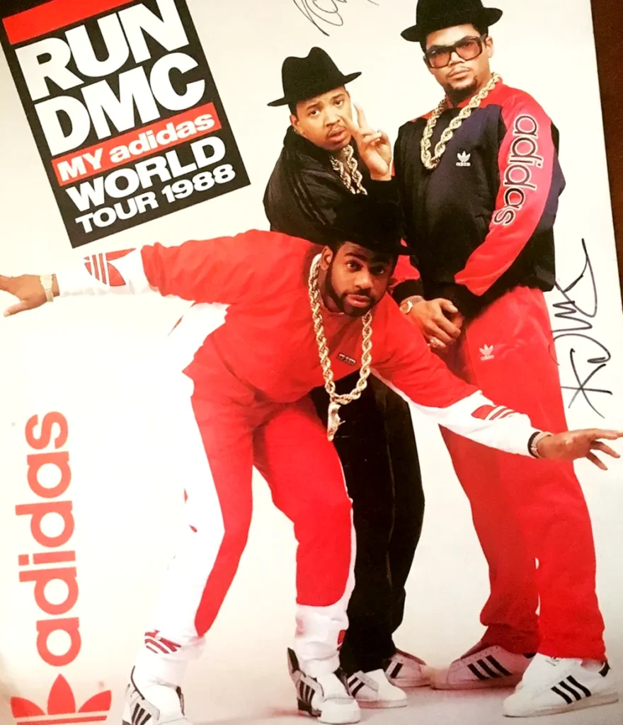 A promotional poster for Run DMC's 1988 "My Adidas World Tour," featuring the three members in red tracksuits and Adidas sneakers, highlighting their celebrity endorsement partnership with Adidas.