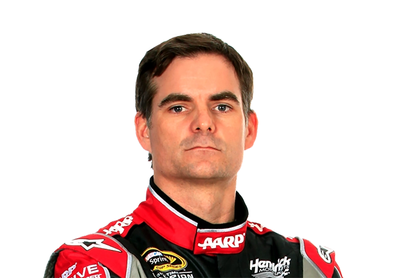 A person wearing a red and black racing suit looks directly at the camera with a neutral expression, embodying the cool confidence often seen in NASCAR celebrity endorsements.