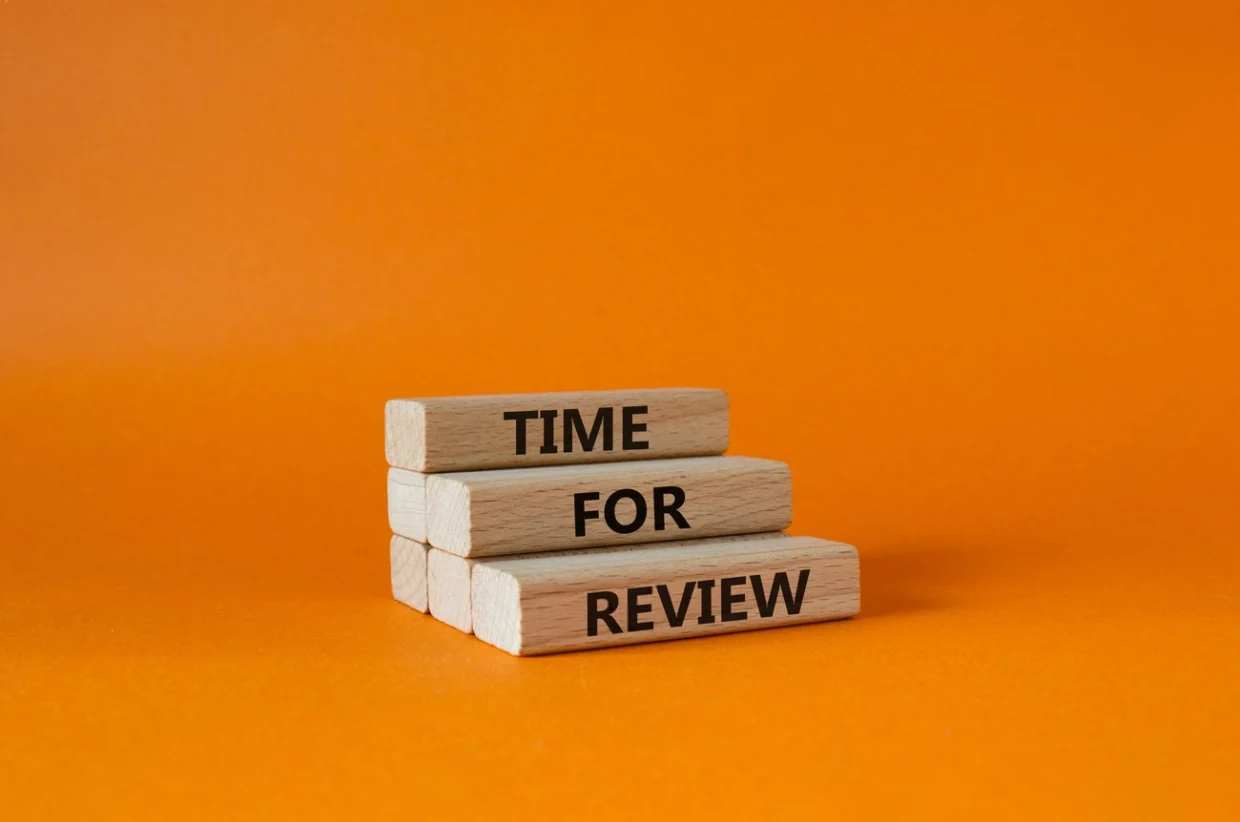 Three wooden blocks stacked on an orange background display the words "TIME FOR REVIEW" in black capital letters, reminding us to reflect and consider examples of good reviews.