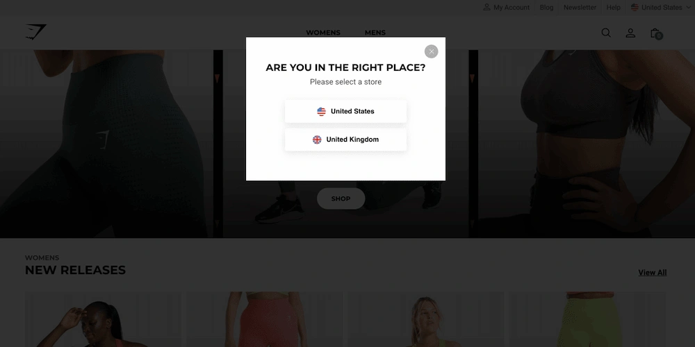 A homepage popup splash page example prompts users to select a store—United States or United Kingdom—appearing over a dimmed background of athletic apparel to boost conversion.
